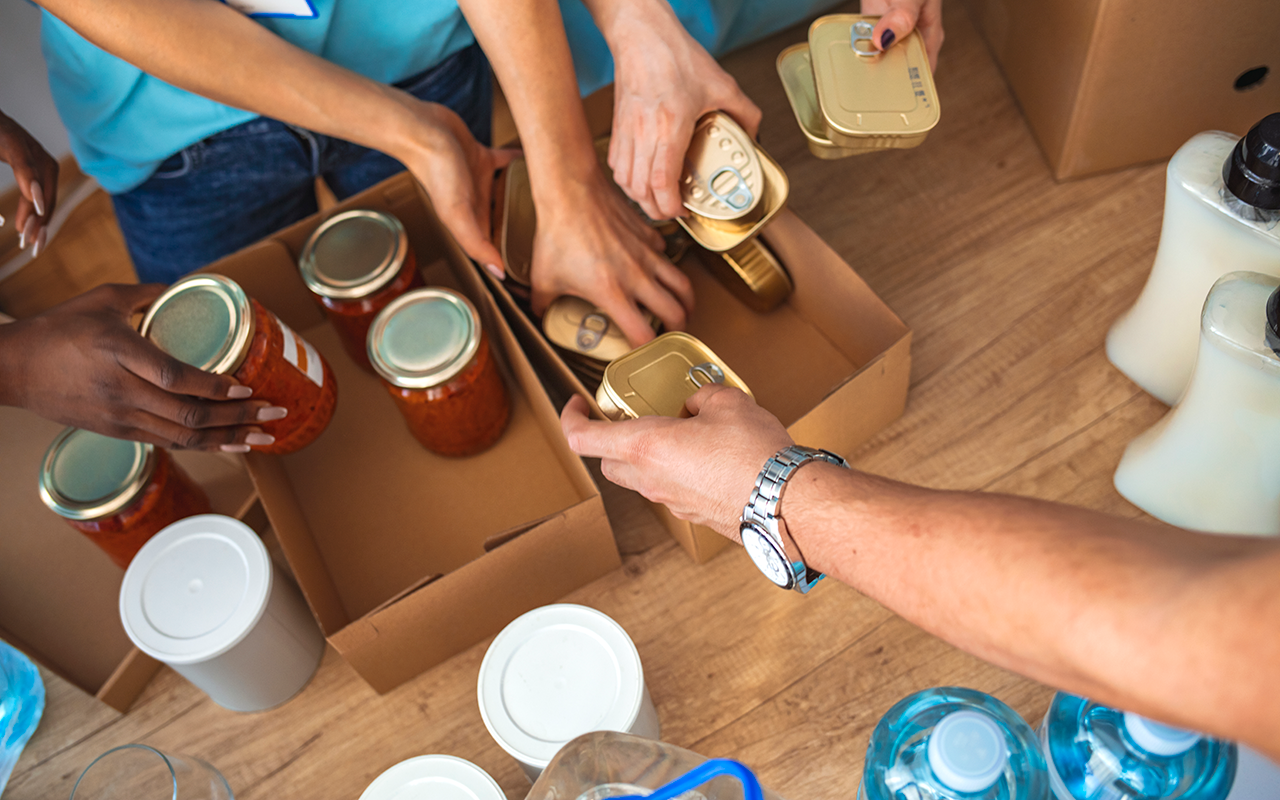Hands pack non perishable food into cardboard boxes