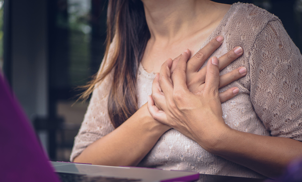 Woman touching breast and having chest pain after long hours work on computer. Office syndrome concept.