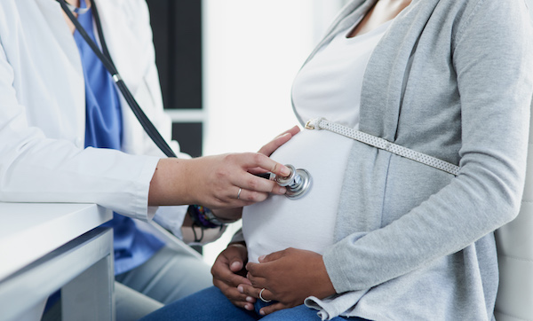 Shot of an female doctor listening to movement inside of a pregnant patient with a stethoscope at a hospital during the day