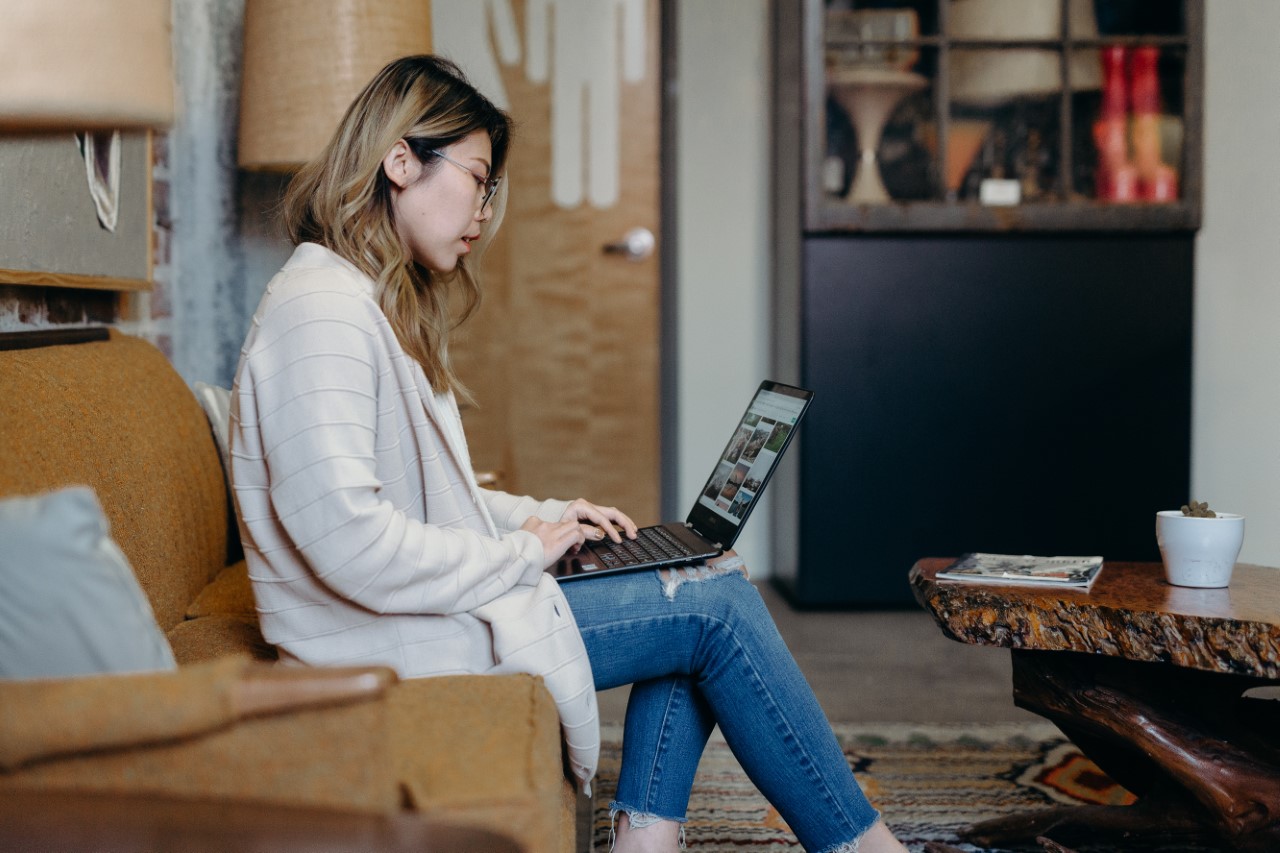 Woman sits on a couch working on laptop
