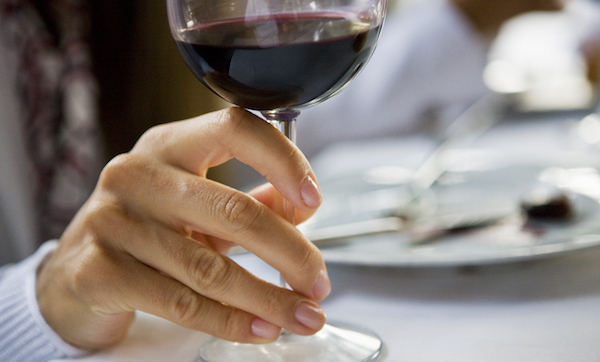 Person holds a glass of red wine