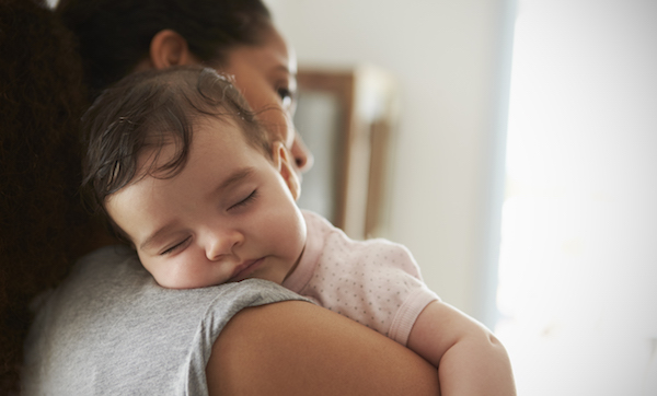 Close Up Of Mother Cuddling Sleeping Baby Daughter At Home