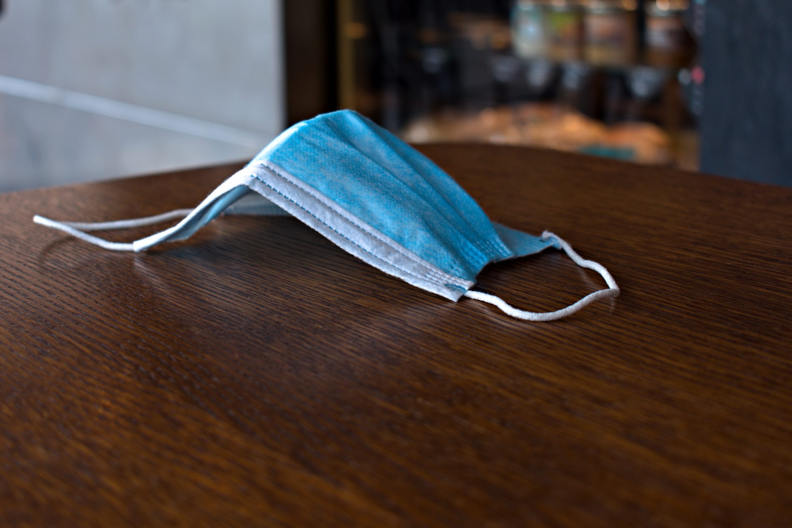 Blue medical anti virus mask close up on blurred wooden table