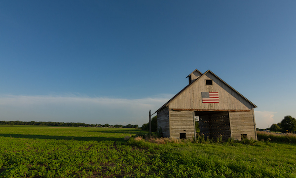 Old wooden barn in the Midwest with American Flag in the afternoon light.