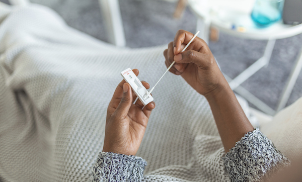 Young African American woman taking a Self-swabbing home tests for COVID-19 at home with Antigen kit