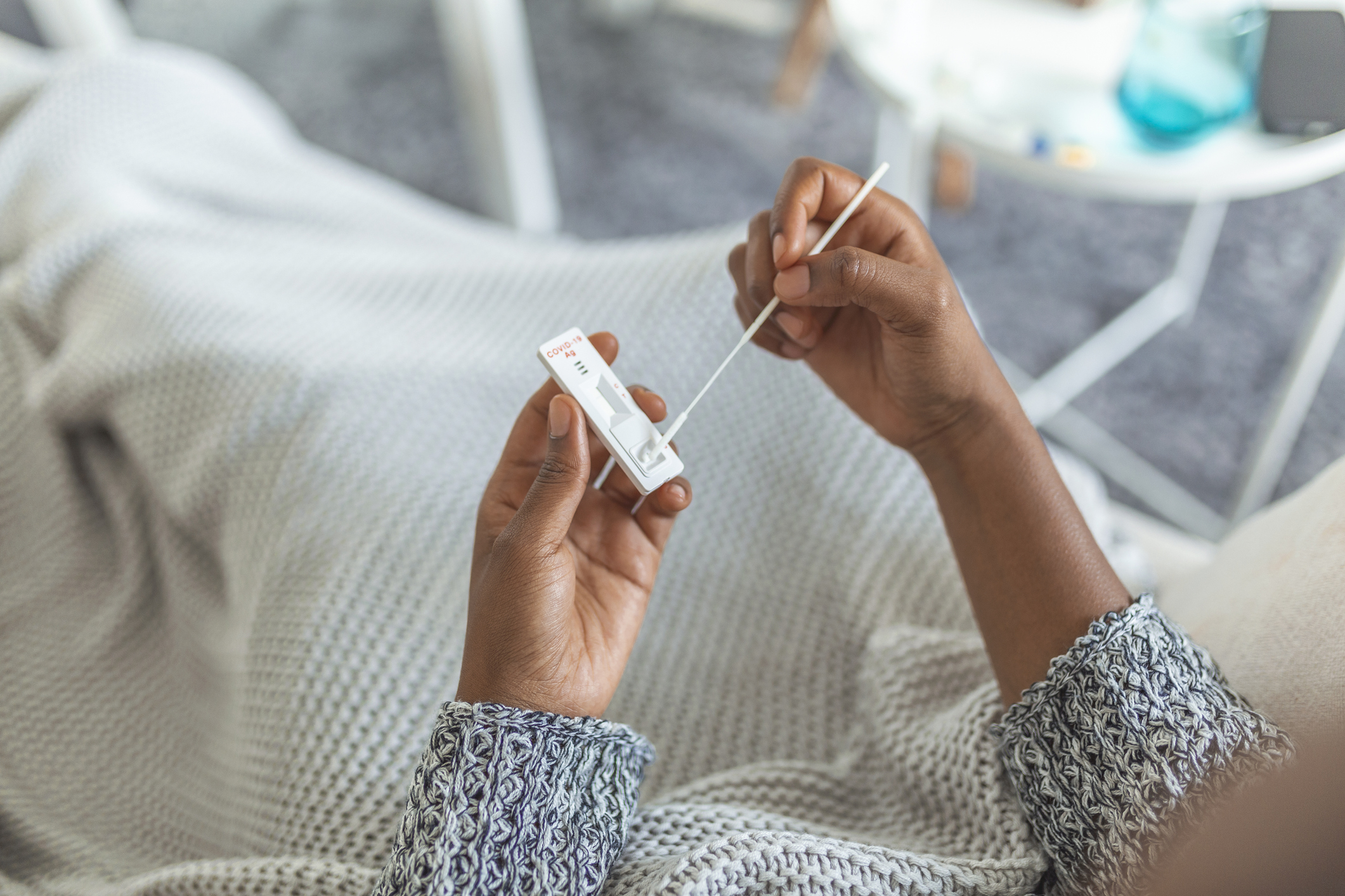 Young African American woman taking a Self-swabbing home tests for COVID-19 at home with Antigen kit