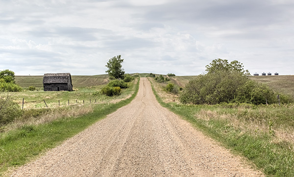 Gravel road with an old barn on the left