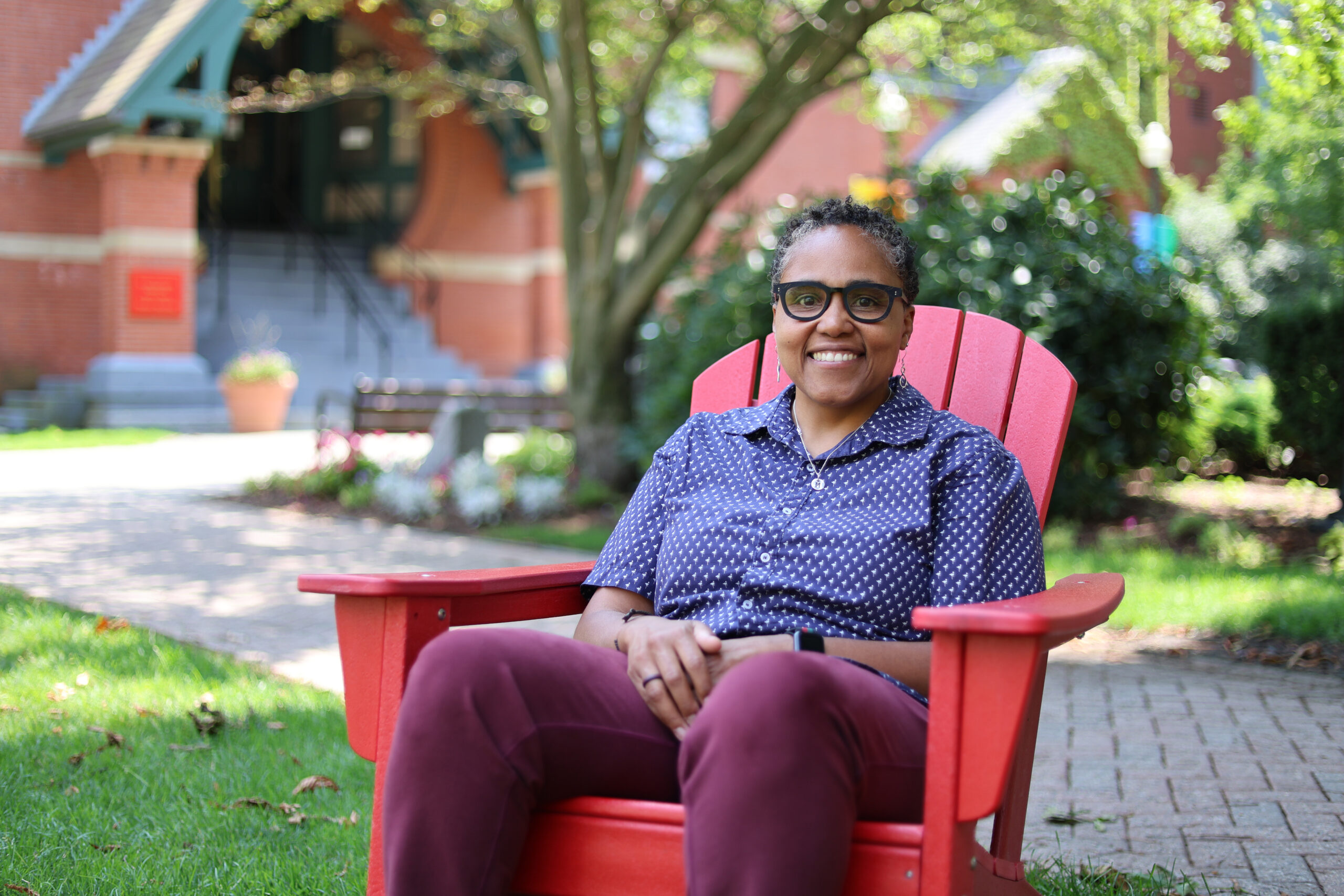 Scarlett Bellamy sits in an Adirondack chair on the BUSPH campus