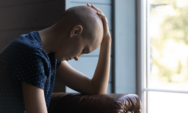 Oncology patient hangs head in hand, picture expresses feelings of sadness and fatigue