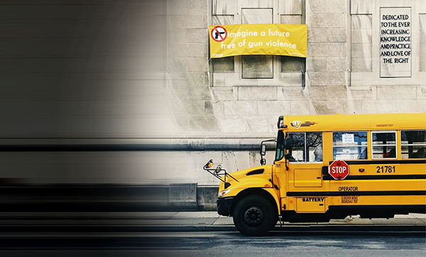 A school bus parked under a sign that reads "imagine a future free of gun violence"