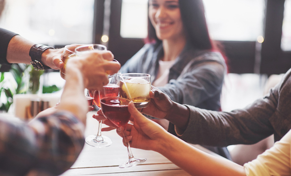 Hands of people with glasses of whiskey or wine, celebrating and toasting in honor of the wedding or other celebration.