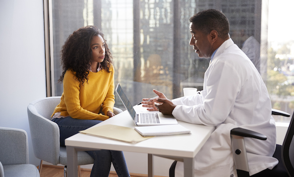 Serious Woman Having Consultation With Male Doctor In Hospital Office