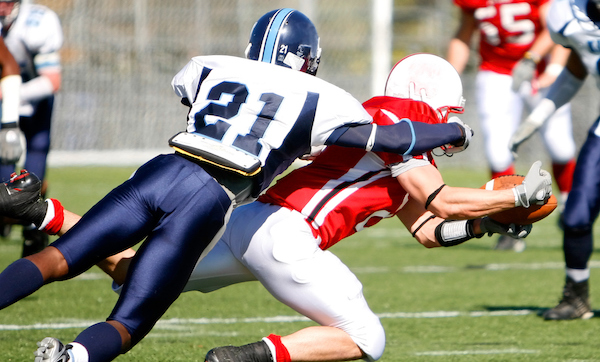 The running back dives for the first down with the defender on his back.