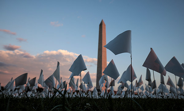Thousands of small white flags planted in the grass with the Washington Monument in the background