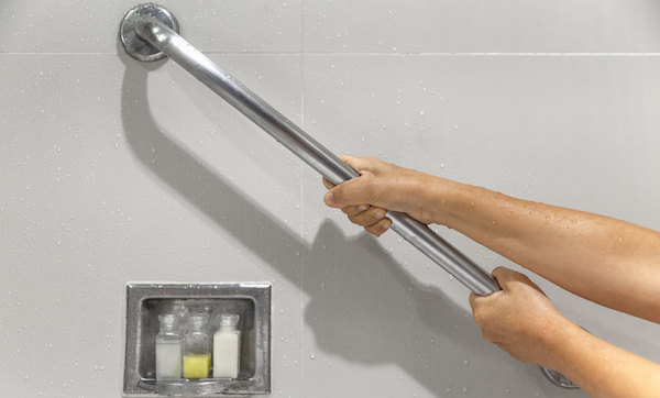 Senior woman holding on handrail for safety in bathroom