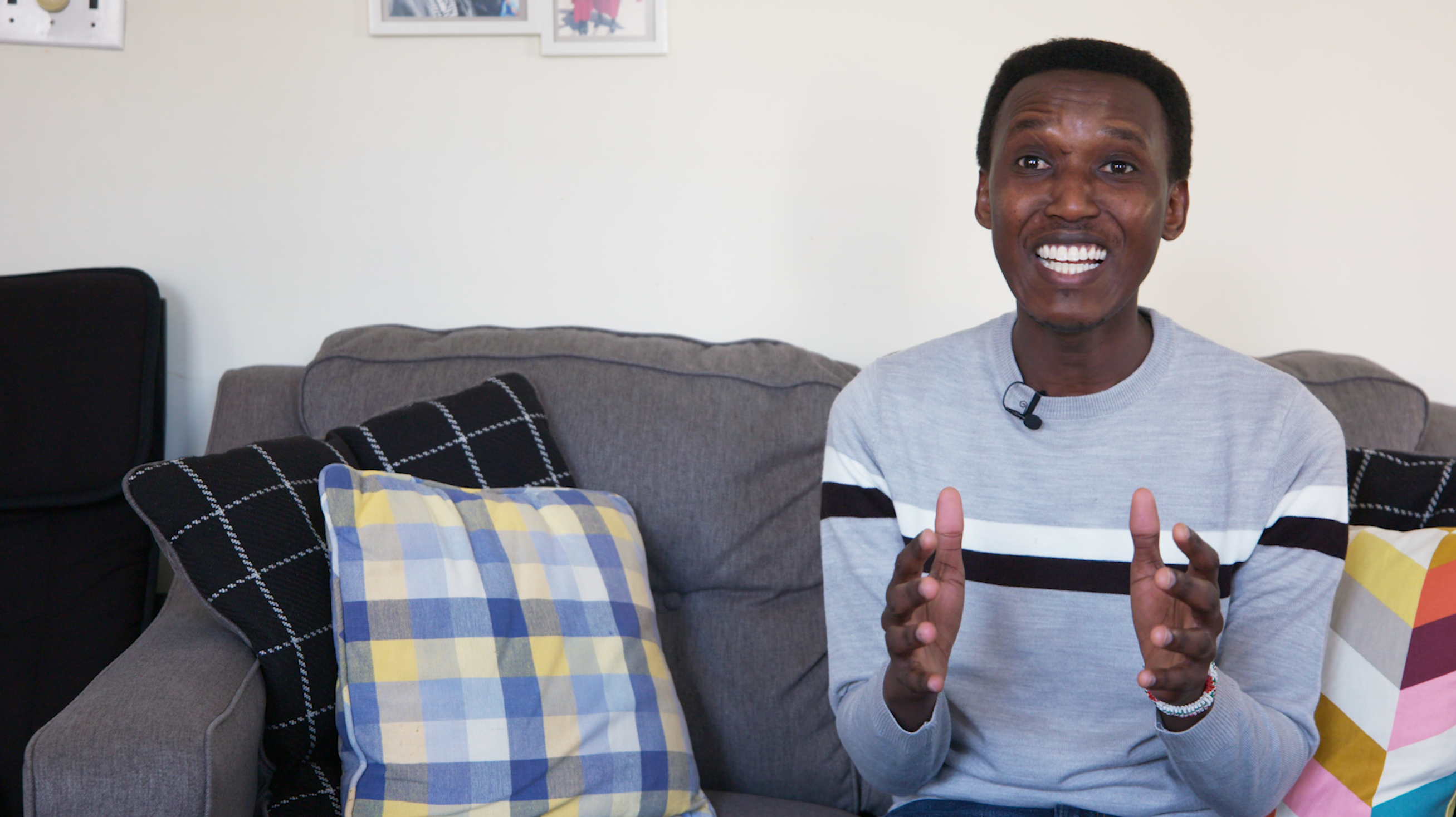 Alex Gitungano, sits on a couch, smiling and gesturing with his hands mid-conversation