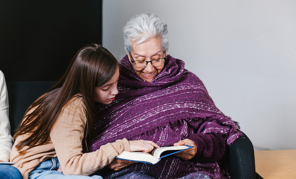 Latin granddaughter and mexican grandmother reading a book and tablet in Mexico city