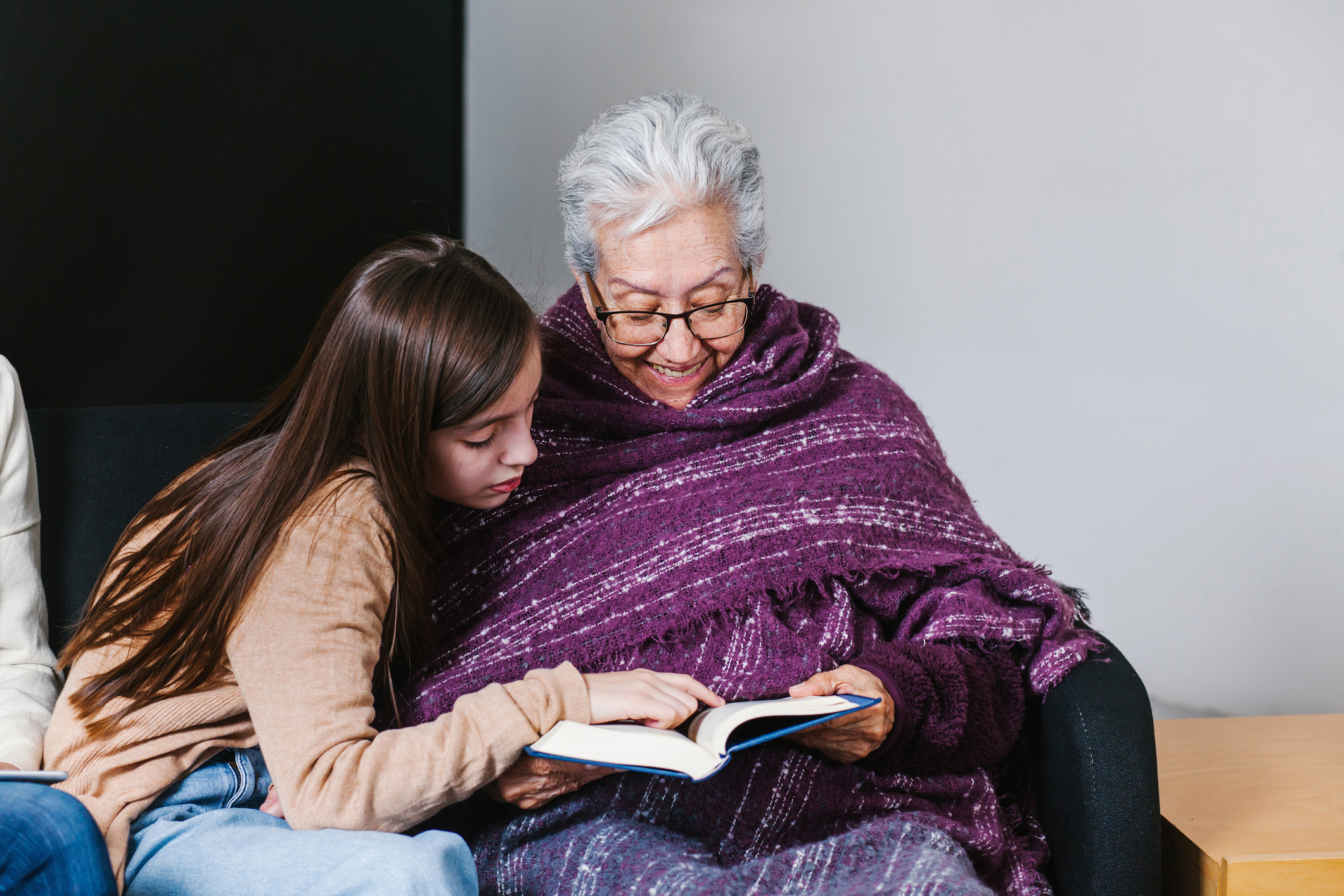 Latin granddaughter and mexican grandmother reading a book and tablet in Mexico city