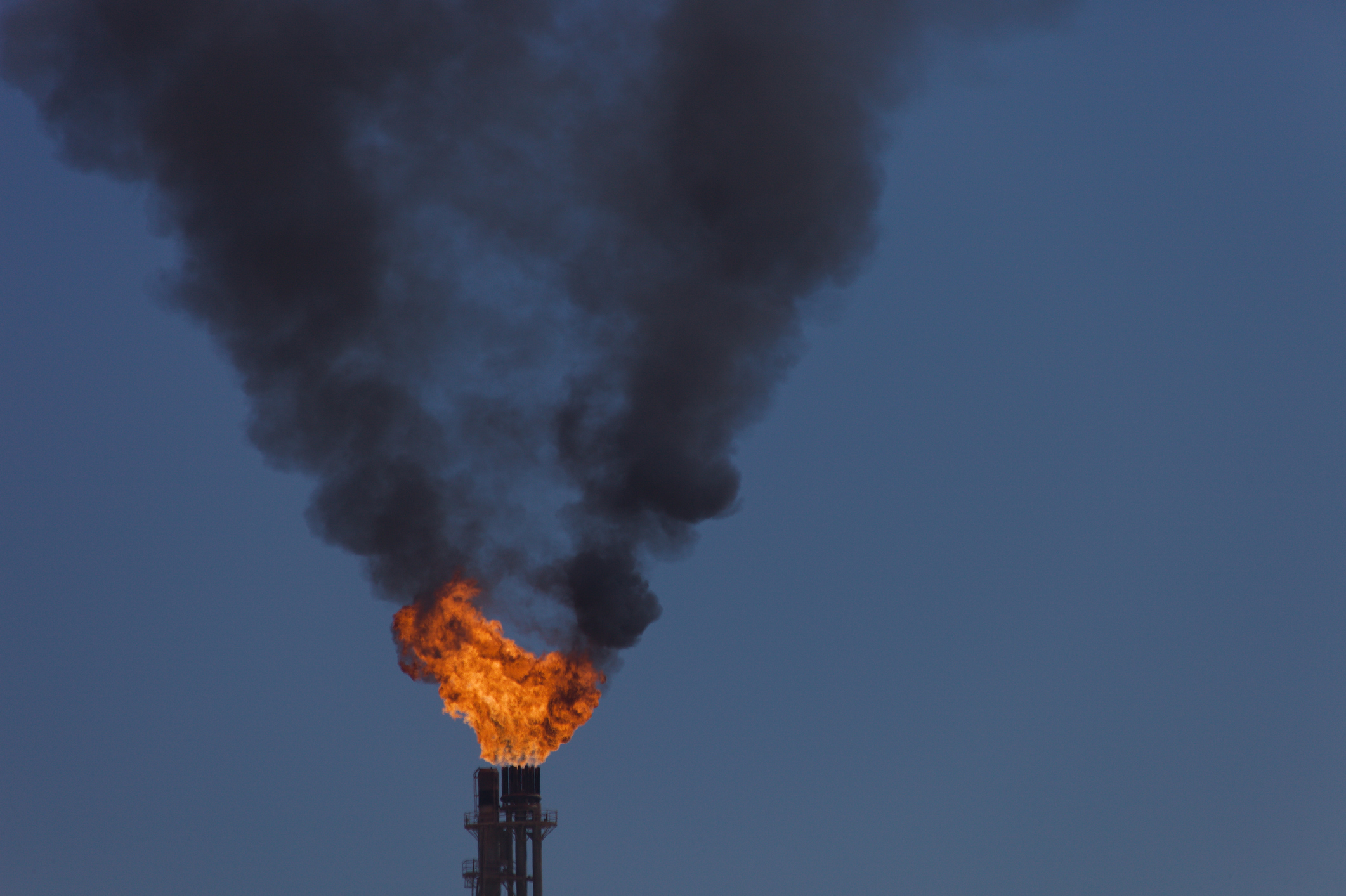 Closeup of gas flare and dense black smoke in the sky