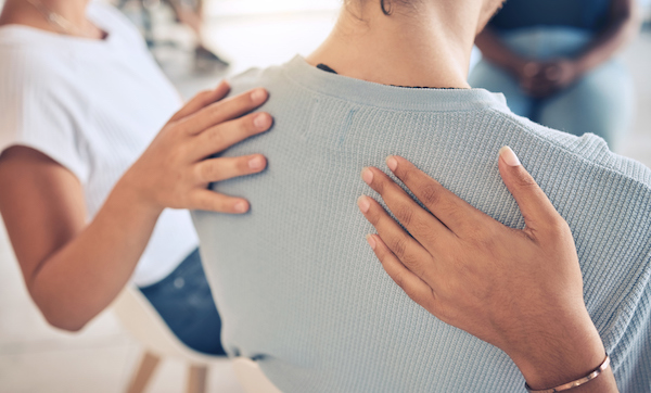 Hands on the back of a woman, people and aa meeting by community in trust, help and empathy for girl with anxiety