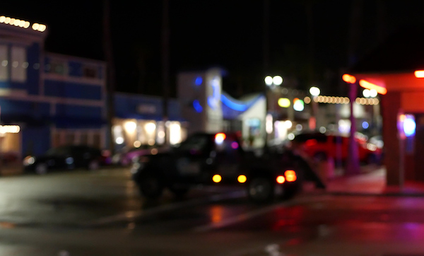 Defocused evening street, blurred bokeh. Lights of city and cars on rainy night. Reflection of electric lamps. Automobiles on road in soft focus. Twilight illuminated town, Oceanside, California USA.