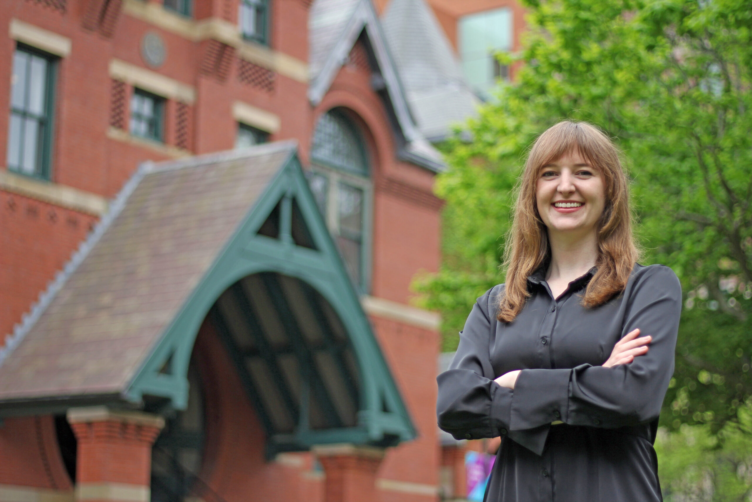 Charlotte Greenhill stands with arms crossed in front of the Talbot Building