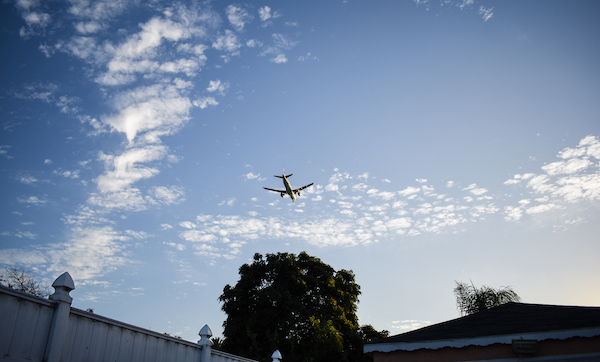 A commercial plane flying over a residential area in the afternoon