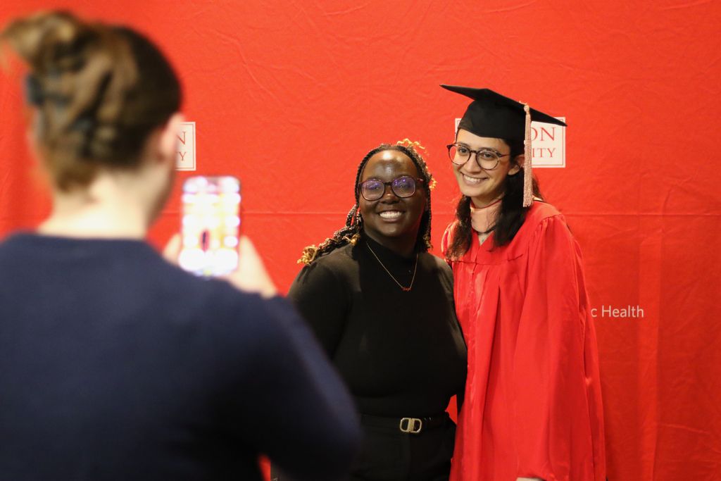 A graduate and friend take photos at the 2024 December Graduate Reception