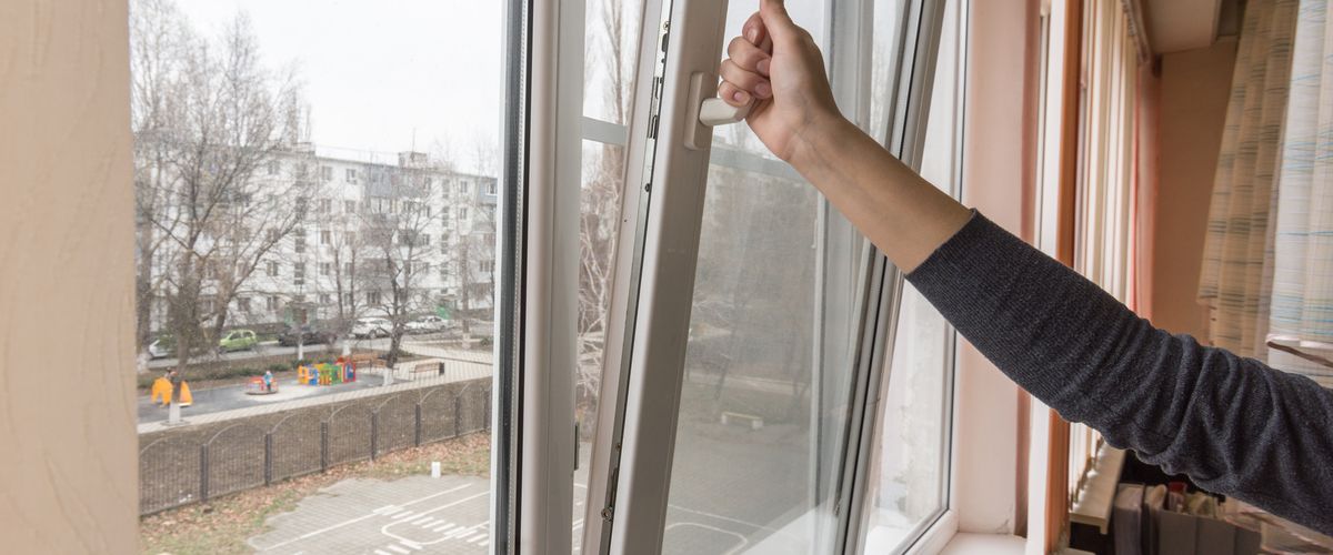 A hand opens a window to air the room