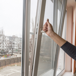 A hand opens a window to air the room