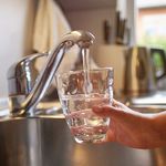 Close up of children hands, pouring glass of fresh water from tap in kitchen