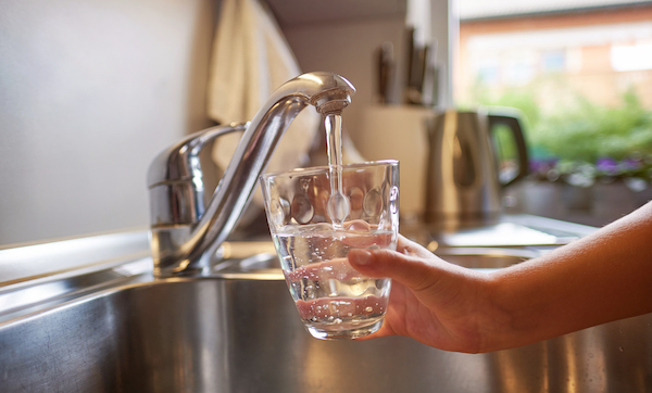 Close up of children hands, pouring glass of fresh water from tap in kitchen