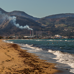 Environmental problem of pollution of environment and air in large cities. Factory for the production of electricity near the sea on the beach (Greece, island Crete)