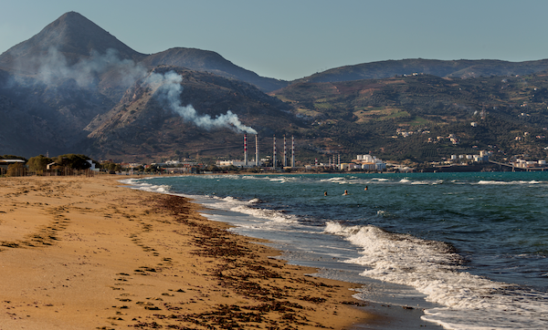 Environmental problem of pollution of environment and air in large cities. Factory for the production of electricity near the sea on the beach (Greece, island Crete)