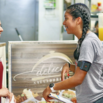 Victoria A. Lopez (right), an MPH student, explains how the wearable temperature sensor on her left arm works to a potential study participant at a restaurant in Chelsea.