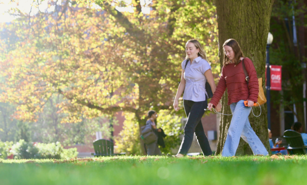 Students walk across campus surrounded by fall foliage.