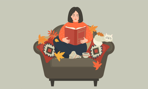 Autumn mood. Woman reads book sitting in cozy armchair at home.