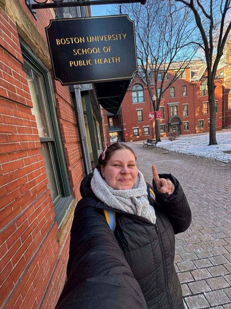 Bella Fletcher poses with the Boston University School of Public Health sign outside the Talbot Building.
