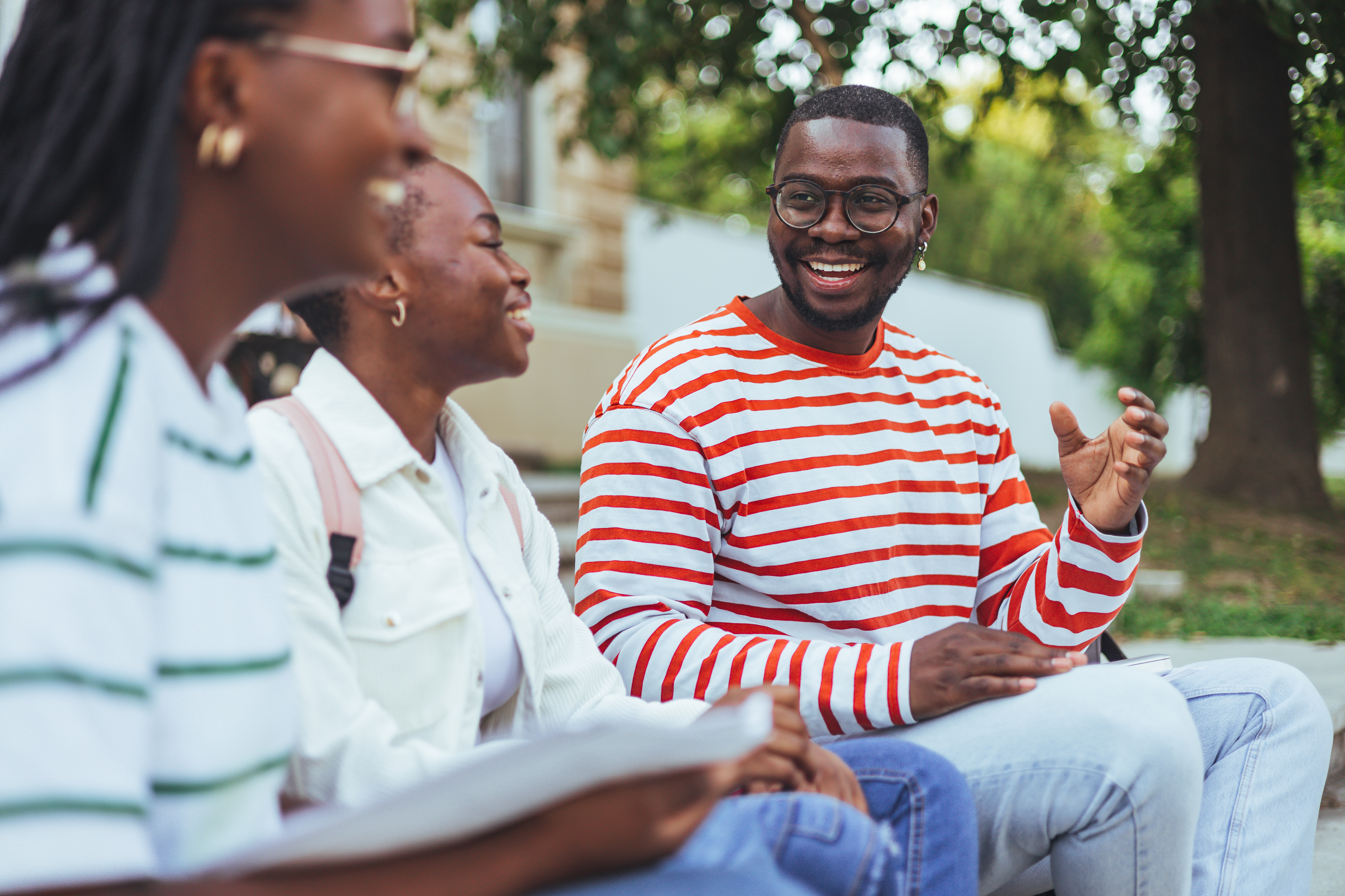 Group of three happy multiethnic friends talking outdoors. Portrait of young people of African American enjoying vacation together. Three african american friends outdoor.