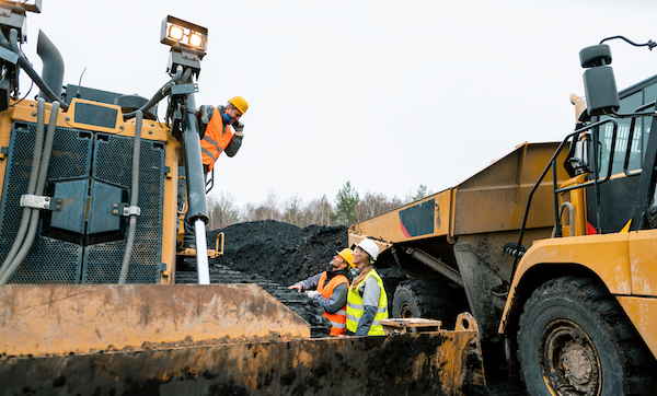 Heavy machinery and workers in pit of quarry shouting at each other because the noise is unbearable