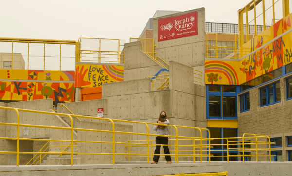 Patricia Fabian walks across the roof of Josiah Quincy Elementary School in Chinatown on July 15, 2026. A sepia-toned haze blankets the sky as she surveys the building for indicators that the severe pollution event might impact the school's indoor air quality. Photo: Megan Jones