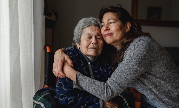 Portrait of woman in wheelchair hugging daughter with positive face. Third age, Home care concept.