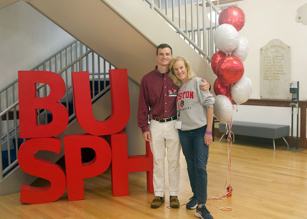 An incoming DrPH student from Pennsylvania poses with his mother next to large, stacked letters spelling "BUSPH" in the Talbot Lobby. Photo: Megan Jones