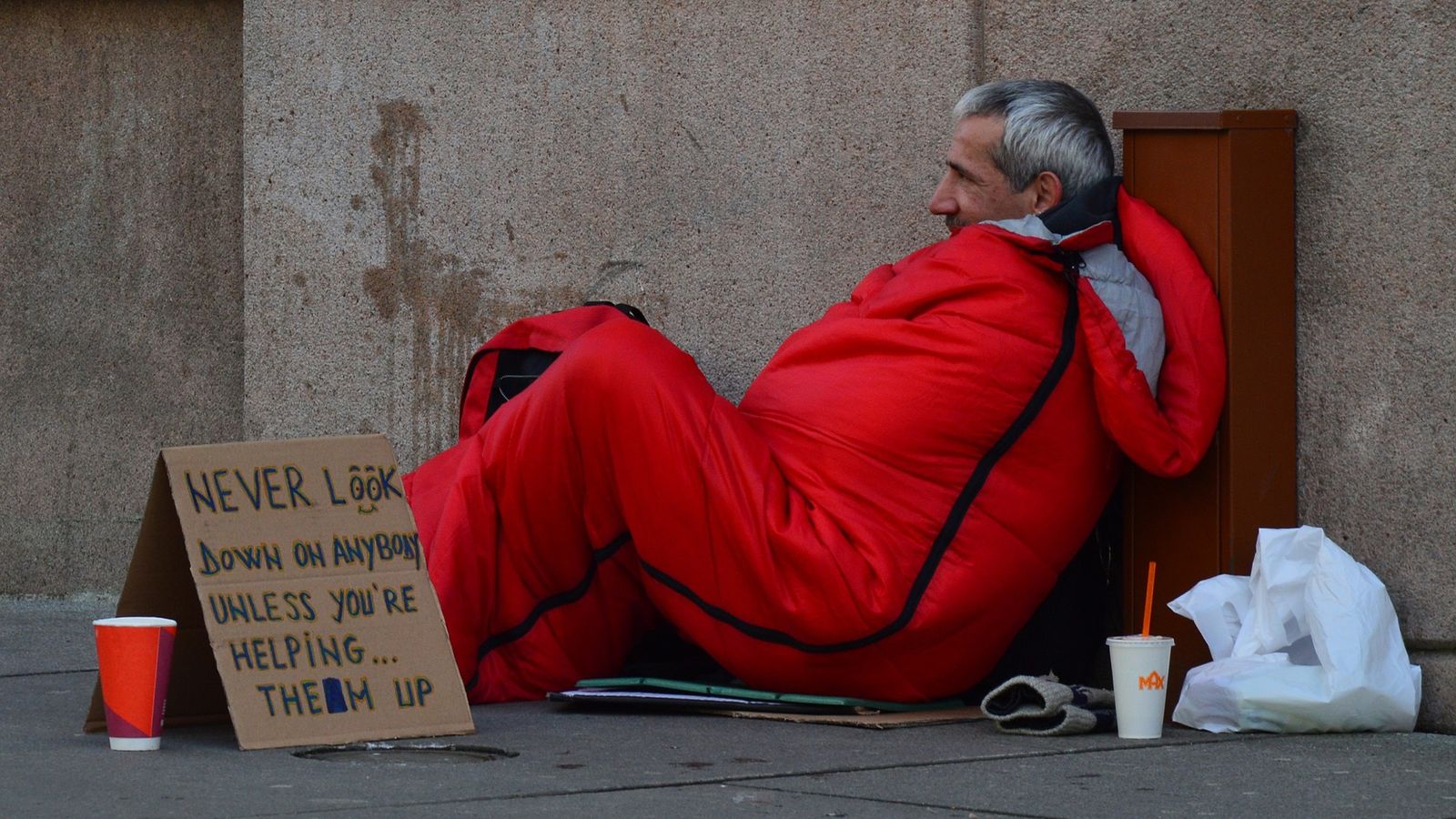 homeless-man-in-sleeping-bag-with-sign