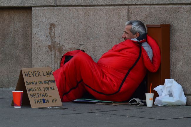 homeless-man-in-sleeping-bag-with-sign