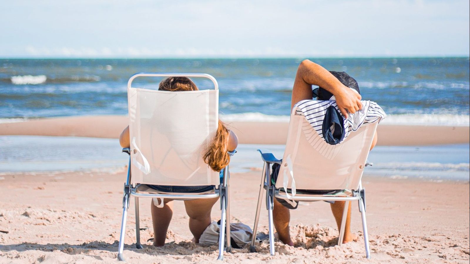two people vacationing on a beach facing the ocean