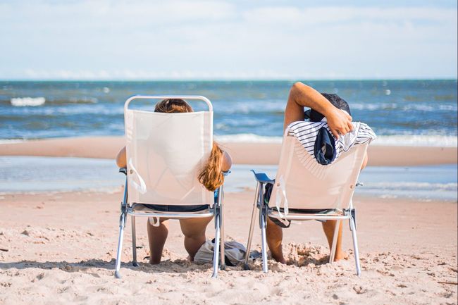 two people vacationing on a beach facing the ocean