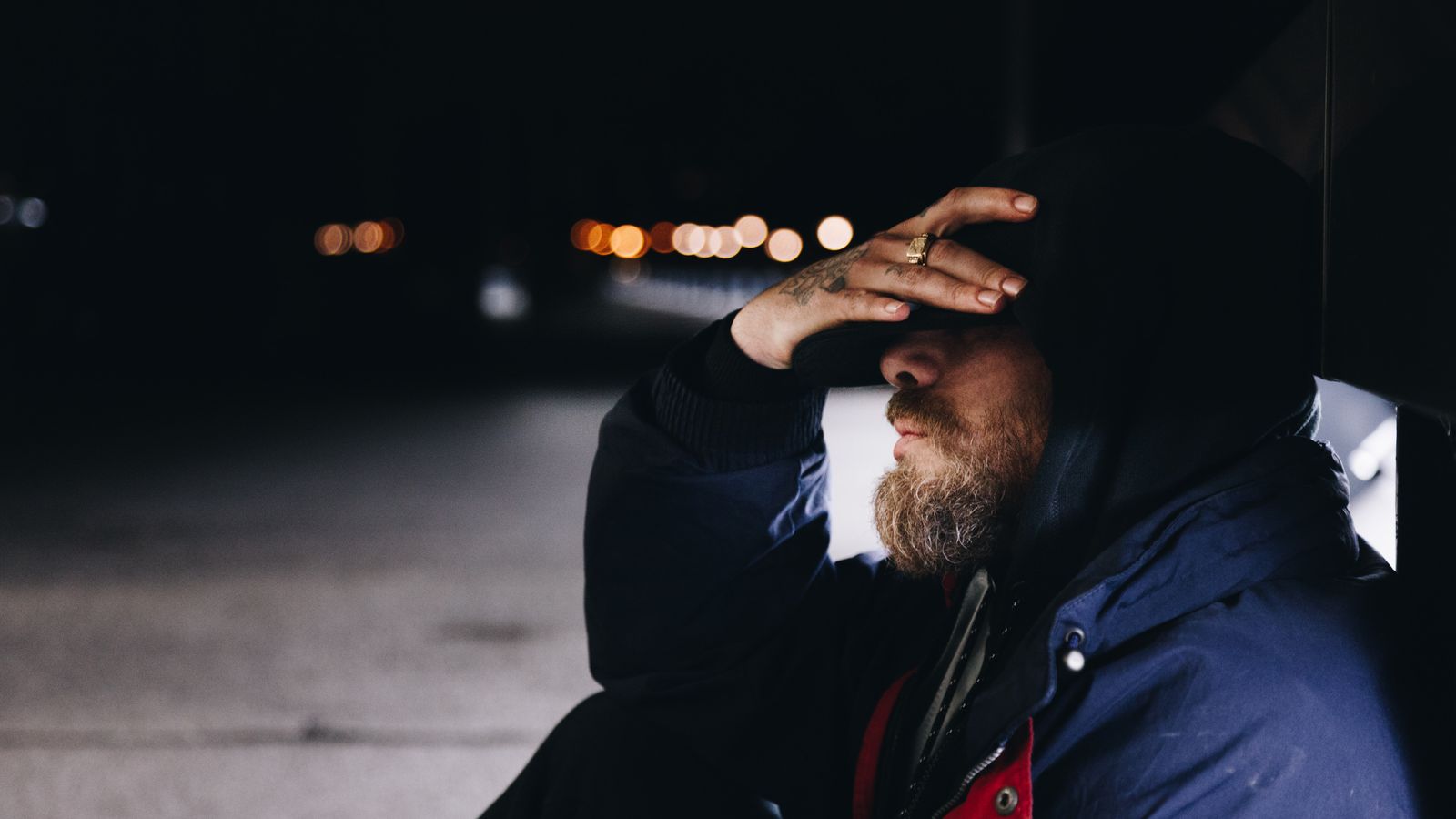 man sits on ground with head in hands