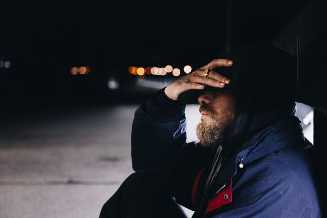 man sits on ground with head in hands