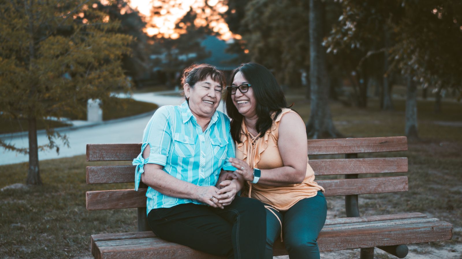 mother and daughter laughing on bench